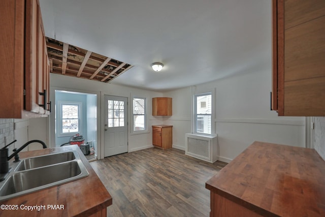 kitchen featuring dark wood finished floors, radiator, brown cabinets, wooden counters, and a sink