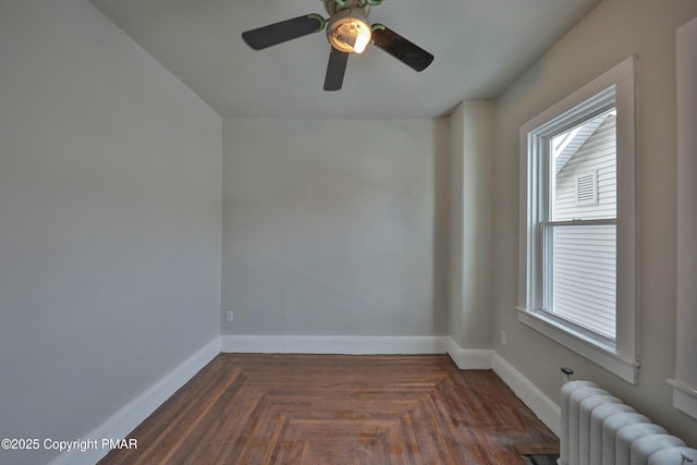 empty room with radiator heating unit, a ceiling fan, and baseboards