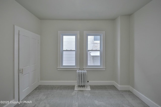 empty room with radiator, carpet, and baseboards