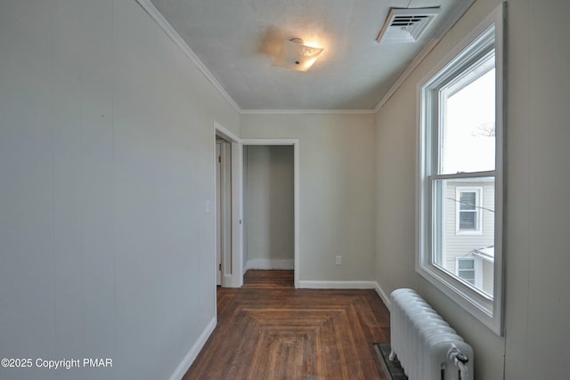 empty room with ornamental molding, baseboards, visible vents, and radiator heating unit