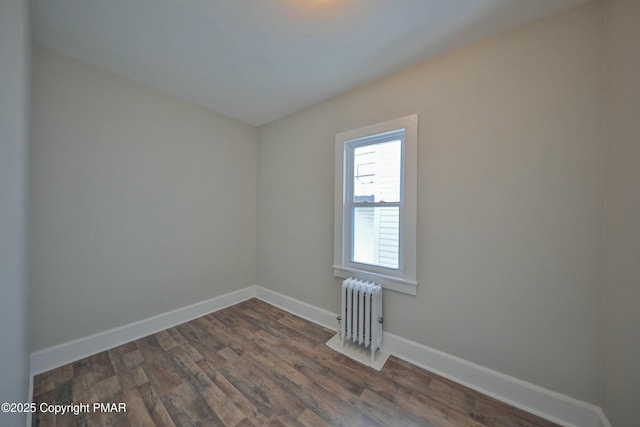 empty room with radiator, dark wood finished floors, and baseboards