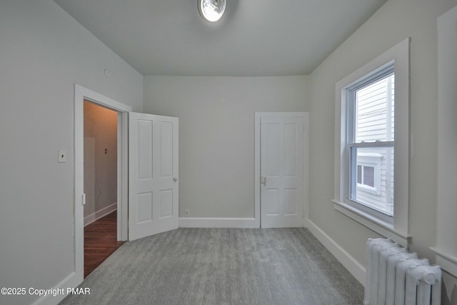 spare room with carpet flooring, baseboards, and radiator heating unit