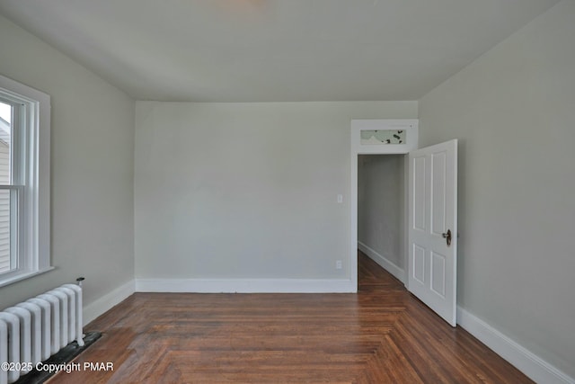 spare room with radiator heating unit and baseboards