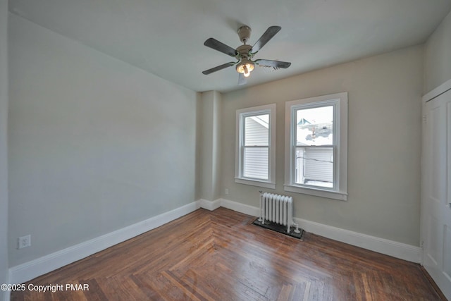 empty room featuring radiator, baseboards, and a ceiling fan