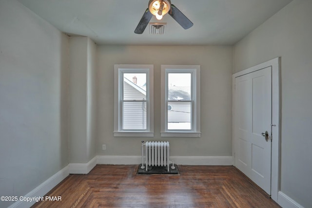 spare room featuring radiator, baseboards, visible vents, and ceiling fan