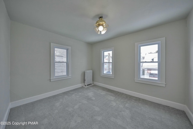 carpeted empty room with baseboards, plenty of natural light, and radiator heating unit