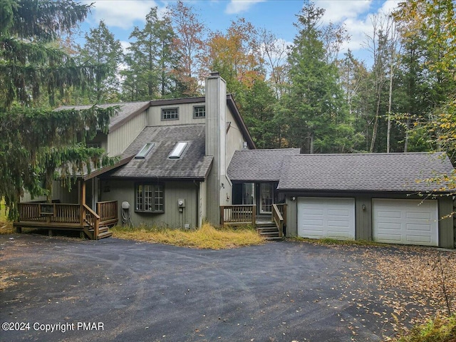 view of front facade with an attached garage, a chimney, driveway, and a shingled roof