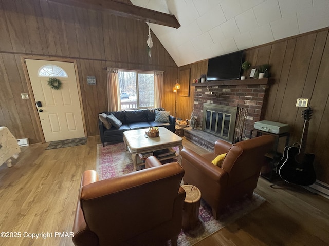 living area featuring beam ceiling, a fireplace, light wood-style flooring, wooden walls, and high vaulted ceiling