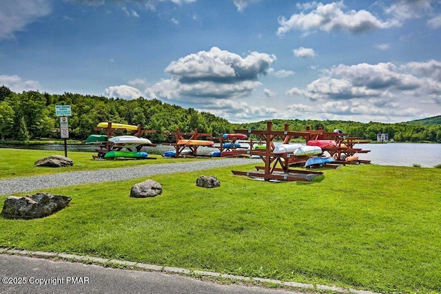 view of home's community with a lawn, a water view, and a view of trees