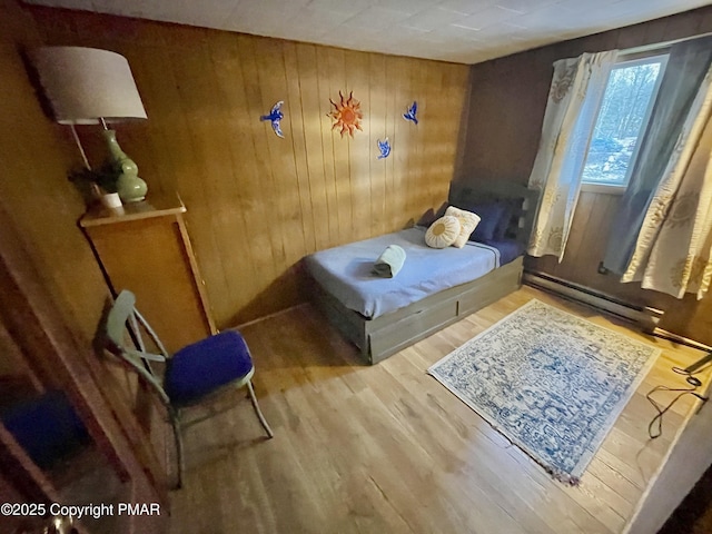 bedroom featuring baseboard heating, wood finished floors, and wooden walls