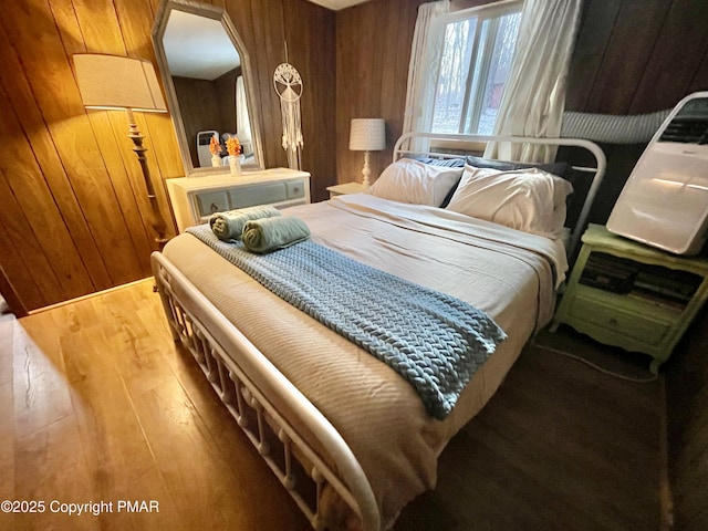 bedroom with wood walls and wood finished floors