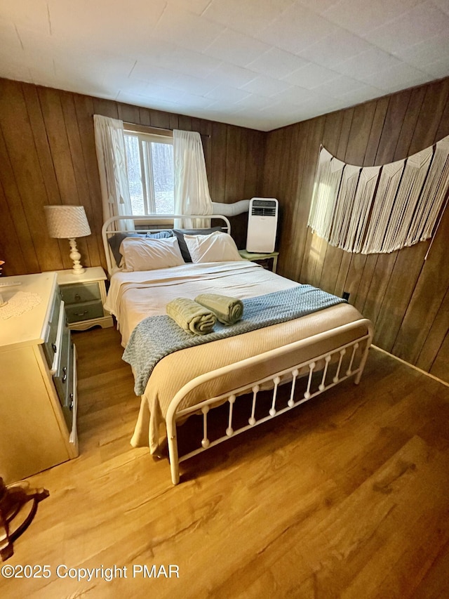 bedroom featuring light wood-style flooring and wooden walls