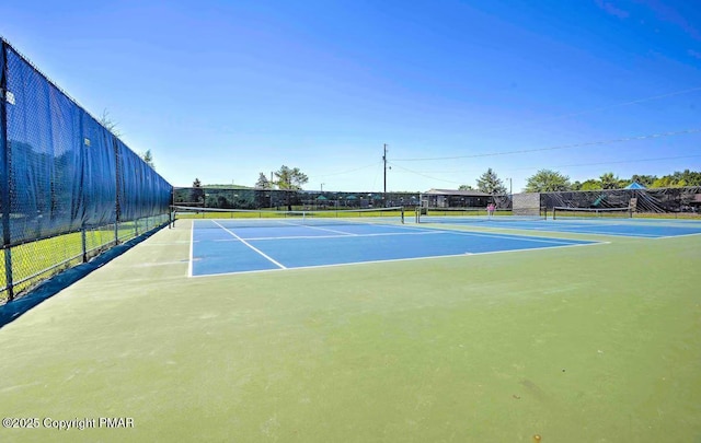 view of tennis court featuring community basketball court and fence