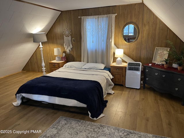 bedroom with lofted ceiling, wood walls, and wood finished floors