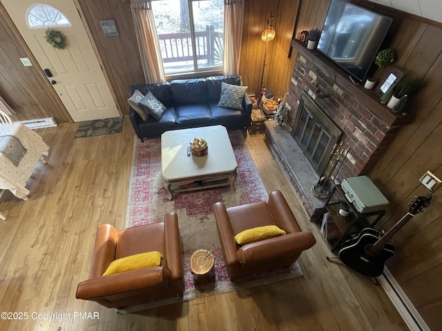 living room with a glass covered fireplace, wood walls, and wood finished floors