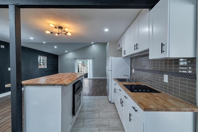 kitchen featuring a center island, black electric stovetop, butcher block countertops, lofted ceiling, and a sink