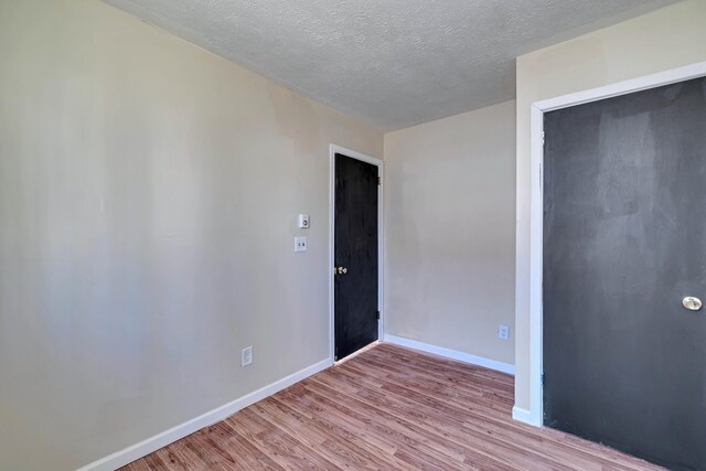 unfurnished room with wood finished floors, baseboards, and a textured ceiling