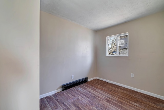 empty room featuring a textured ceiling, baseboards, and wood finished floors