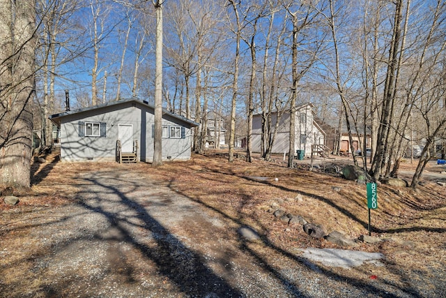 view of property exterior featuring crawl space, driveway, and entry steps