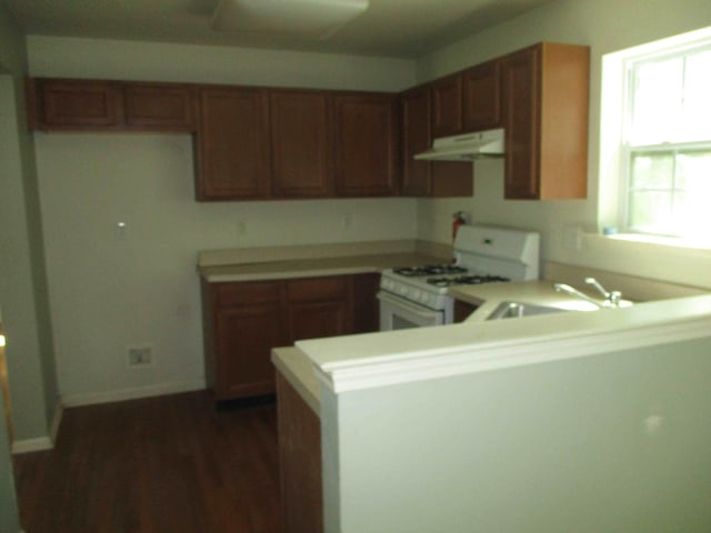 2113 Dorset Ct, Bushkill, PA 18324 - kitchen featuring white range with gas cooktop, under cabinet range hood, a peninsula, light countertops, and dark wood-style flooring