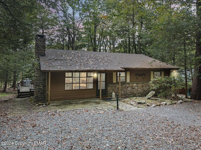 chalet / cabin with stone siding, a patio area, and a chimney