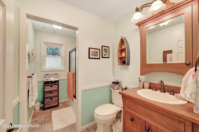 bathroom featuring vanity, a shower stall, toilet, and baseboards