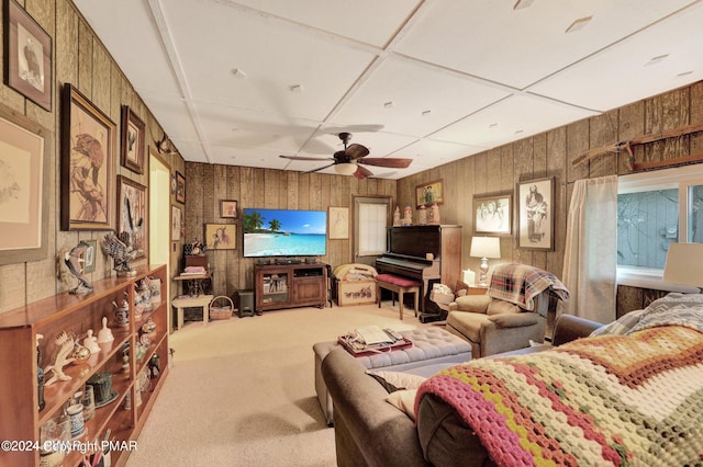 carpeted living room featuring wooden walls and ceiling fan