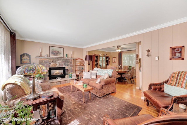 living room featuring a fireplace, crown molding, wood finished floors, and ceiling fan