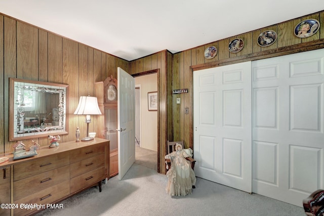bedroom with a closet, light colored carpet, and wood walls