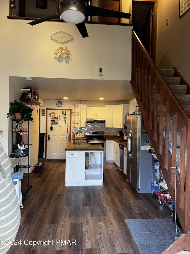 kitchen featuring tasteful backsplash, white cabinets, dark wood-type flooring, stainless steel appliances, and under cabinet range hood