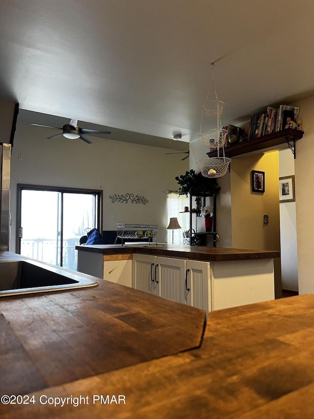 kitchen featuring a ceiling fan, butcher block counters, and white cabinetry