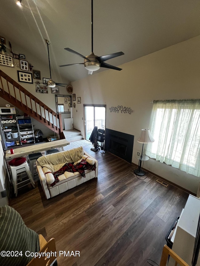 living area featuring a ceiling fan, stairs, high vaulted ceiling, and wood finished floors