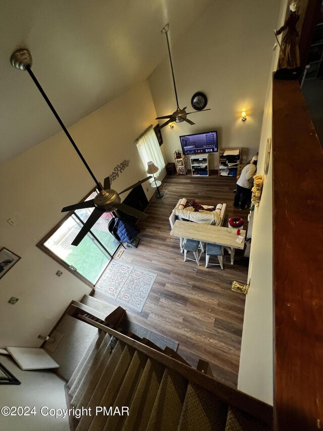 living room with ceiling fan, vaulted ceiling, and wood finished floors