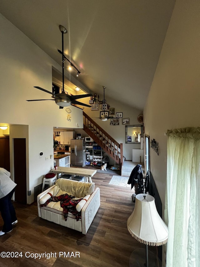 living room with stairs, high vaulted ceiling, ceiling fan, and wood finished floors