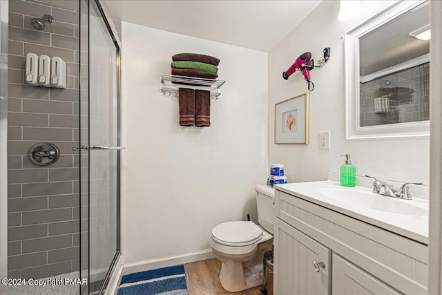 full bathroom featuring toilet, a stall shower, vanity, wood finished floors, and baseboards