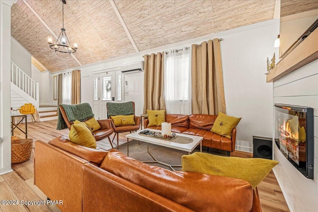 living area featuring a glass covered fireplace, stairway, wood finished floors, a wall mounted air conditioner, and a notable chandelier