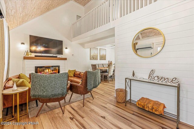 interior space with a wall mounted AC, a high ceiling, wood finished floors, and a glass covered fireplace