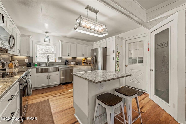 kitchen featuring a breakfast bar, light wood finished floors, stainless steel appliances, and a sink