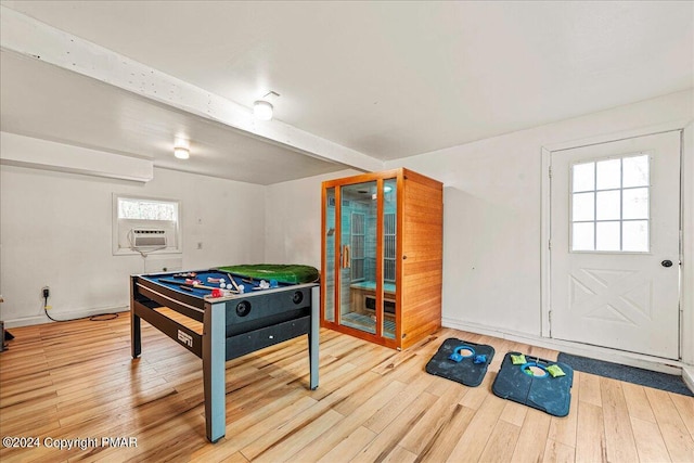 recreation room featuring a healthy amount of sunlight, wood finished floors, and beamed ceiling