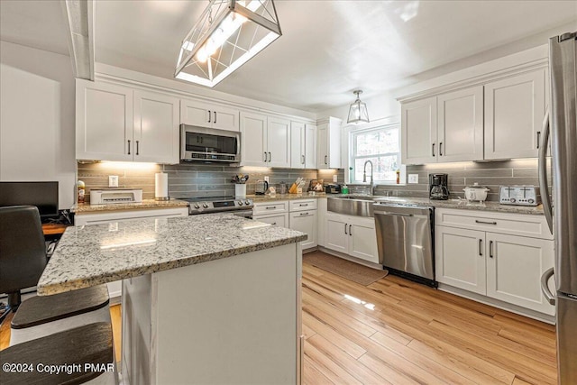 kitchen featuring light wood-type flooring, white cabinets, stainless steel appliances, and a sink