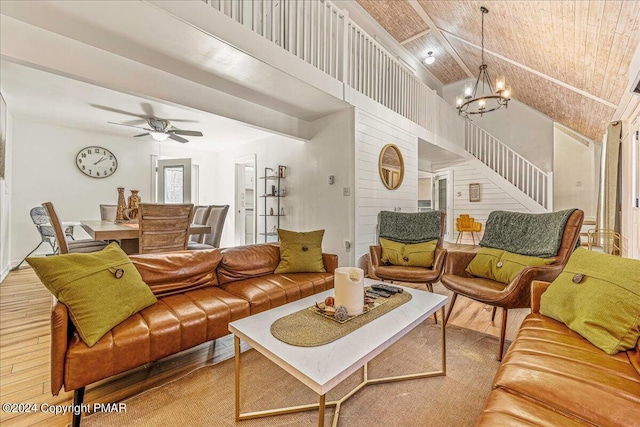 living area with ceiling fan with notable chandelier, a high ceiling, stairway, and light wood-style floors