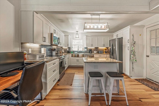 kitchen featuring stainless steel appliances, light stone counters, backsplash, and light wood-style flooring