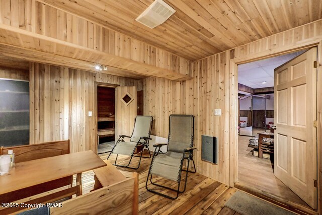 sitting room with wooden ceiling, light wood-type flooring, and wood walls