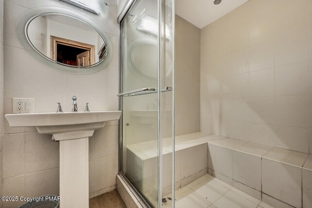 bathroom with an enclosed shower and tile walls