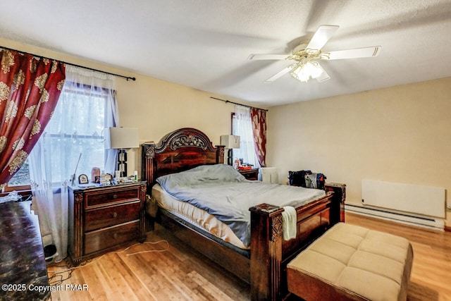 bedroom with a baseboard radiator, ceiling fan, and light hardwood / wood-style flooring