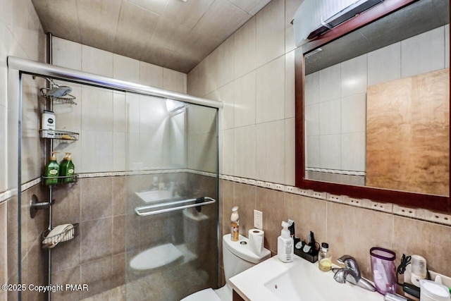 bathroom with vanity, toilet, an enclosed shower, and tile walls