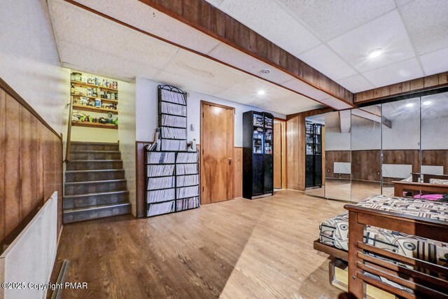 interior space featuring a drop ceiling, hardwood / wood-style flooring, and wooden walls