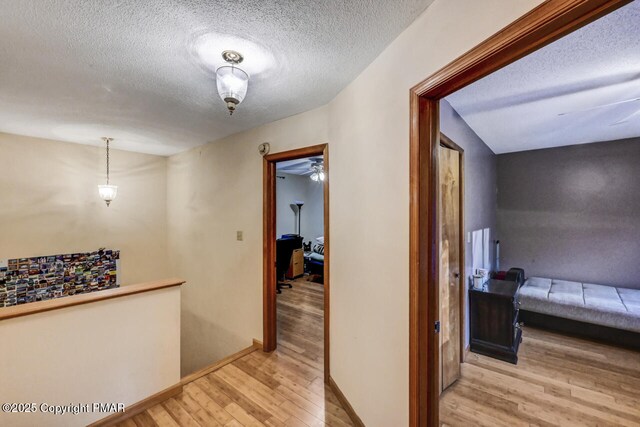 hallway with a textured ceiling and light wood-type flooring