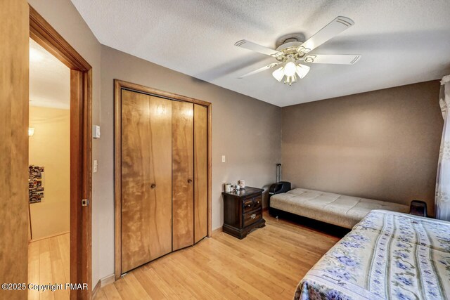 bedroom featuring ceiling fan, a closet, a textured ceiling, and light wood-type flooring