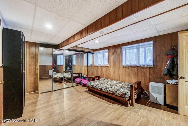 workout room with light hardwood / wood-style flooring, wooden walls, and a paneled ceiling